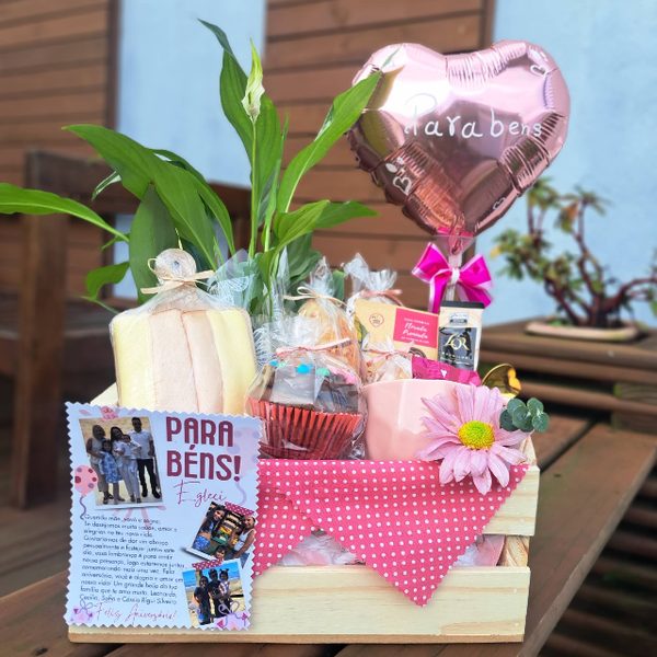 Cesta de aniversário em caixote de madeira com balão coração rosé escrito Parabéns, planta, cupcakes, chocolates e cartão personalizado.